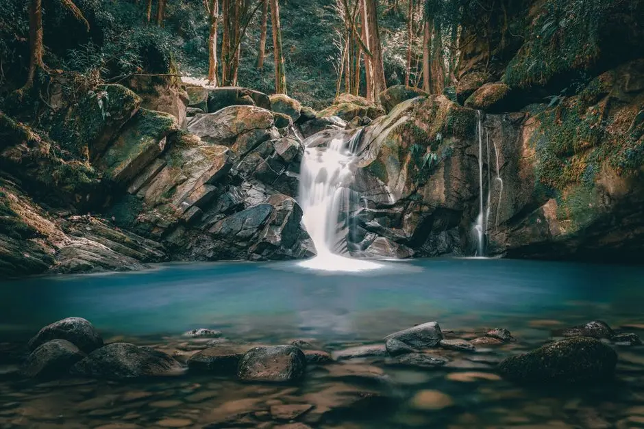 Air terjun Curug Leuwi Hejo dengan kolam hijau toska dan bebatuan alami dikelilingi pepohonan rimbun